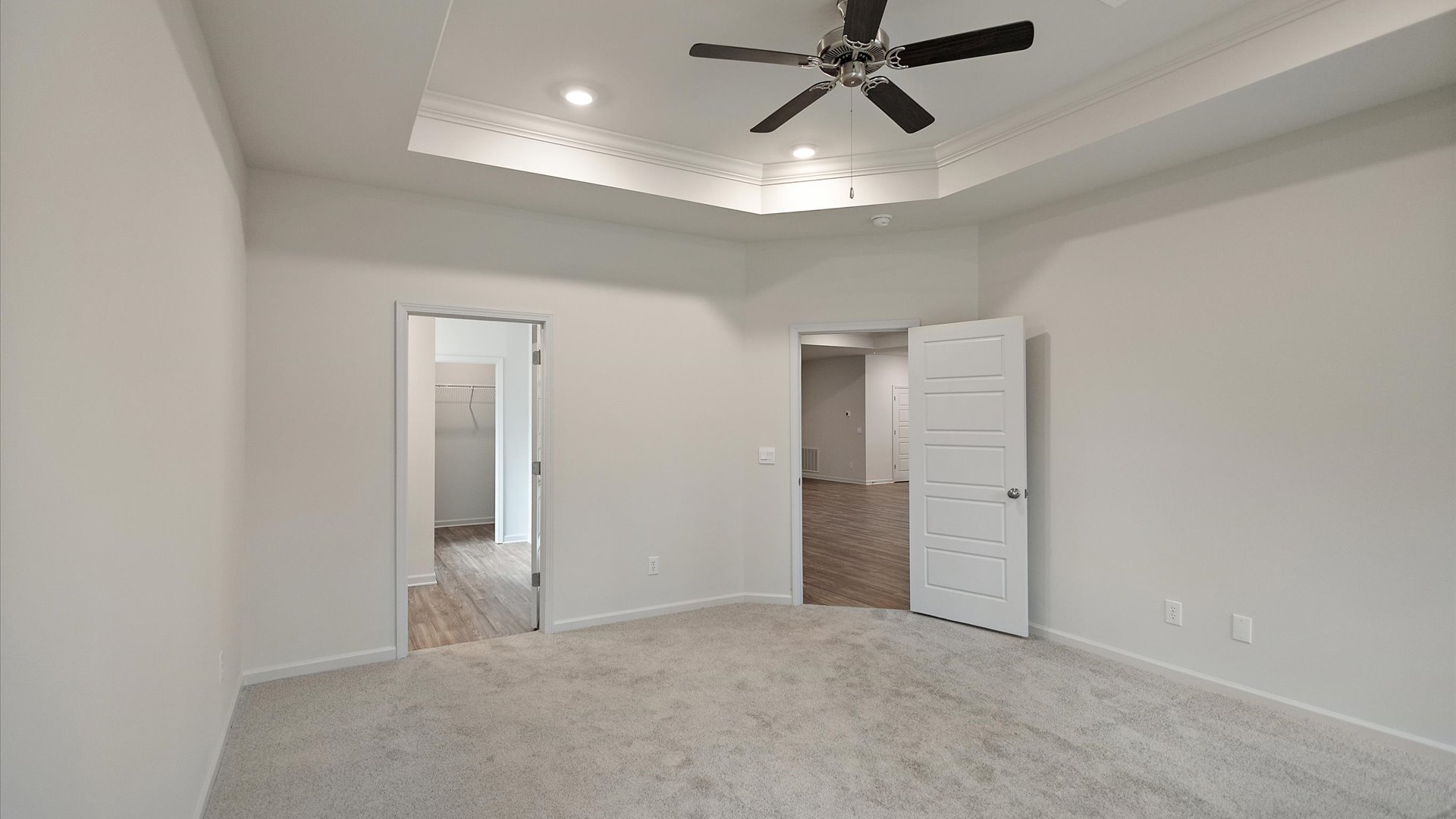 Primary bedroom with carpeted floors, large windows, and trey ceilings.