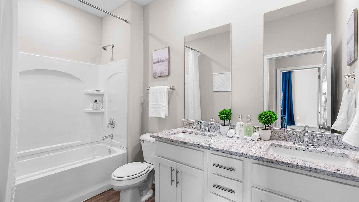 bathroom featuring dual sink vanities, a toilet and a shower