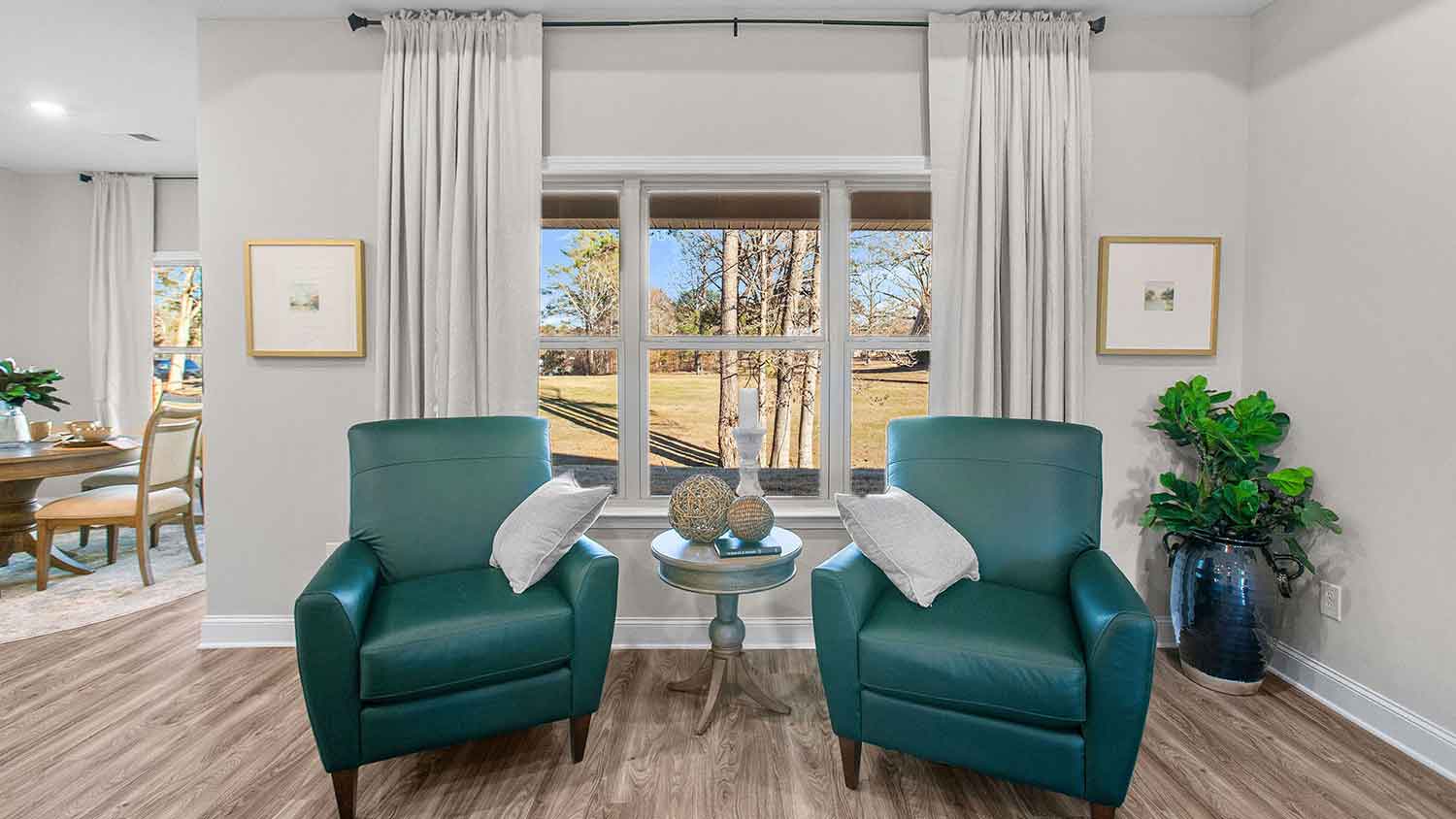 teal accent chairs on either side of the large window off the living room