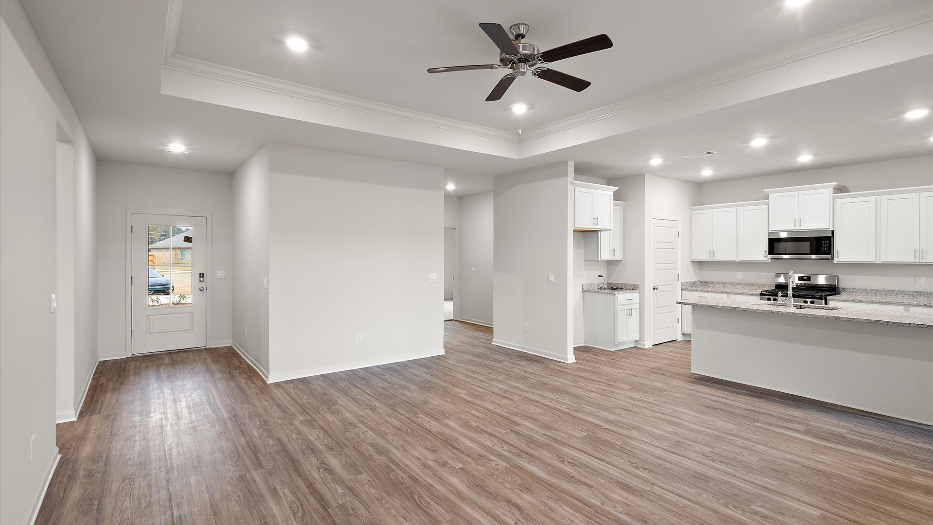 Living space with hardwood flooring, ceiling fan, and recessed lighting