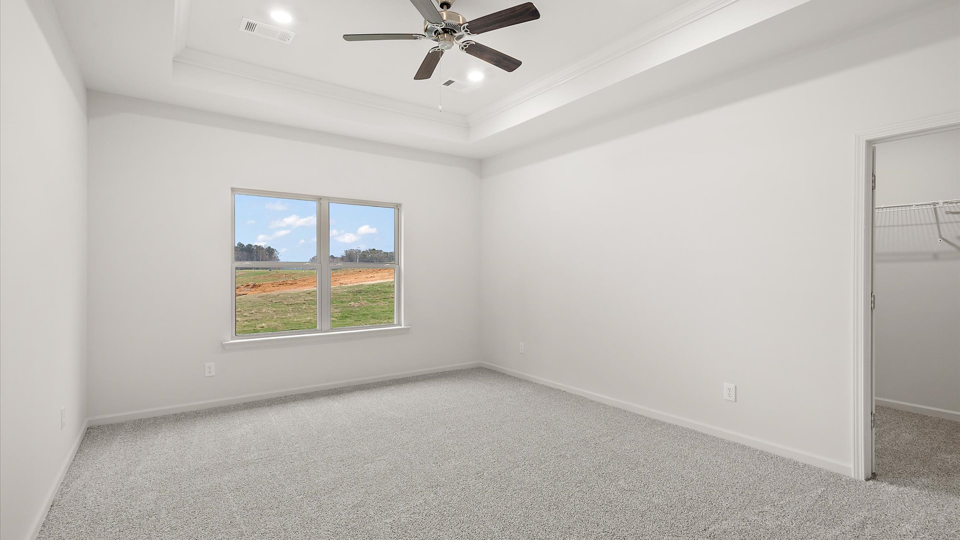 Primary bedroom with carpeted floors, ceiling fan, and window
