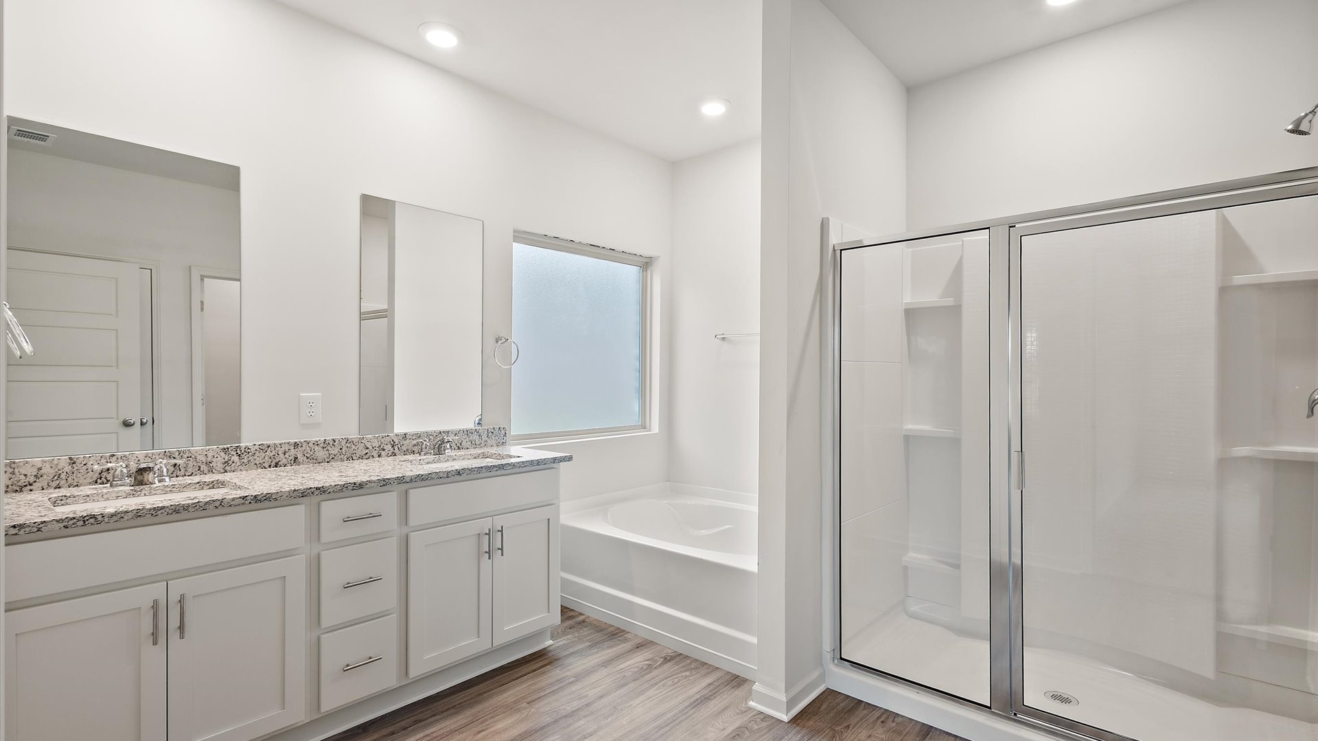 Primary bathroom with double vanity, walk in shower, and garden tub