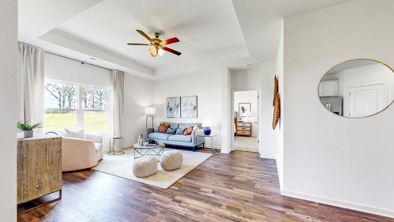 Living room with hardwood floors, trey ceiling, large windows for natural light.