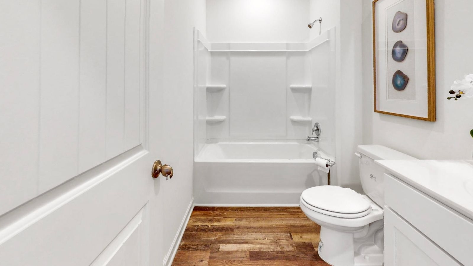 Single vanity with cabinets, mirror, bright light fixtures, and granite countertops with shower tub combination.