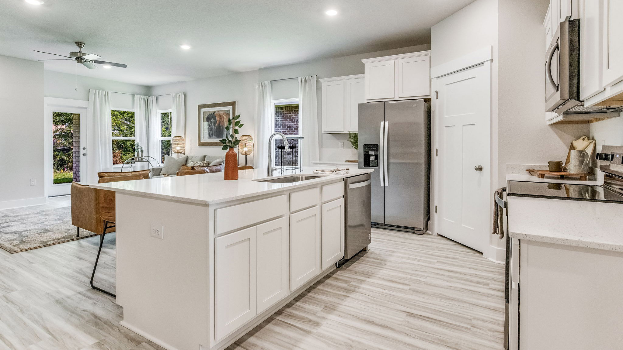 Spacious kitchen with white granite countertops, large white island, white cabinets, and stainless steel appliances.