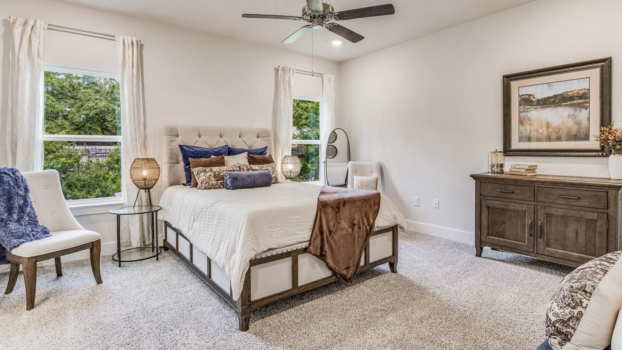 Primary bedroom with carpeted floors, large windows, and trey ceilings.