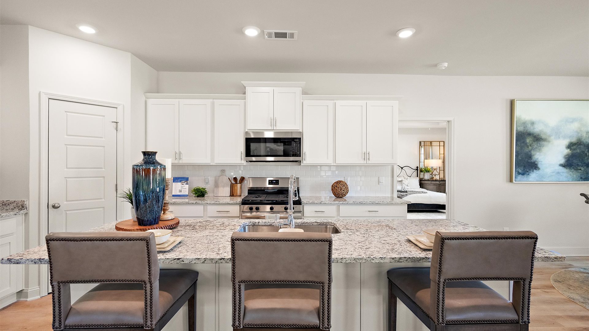 New appliance suite included and central kitchen island with sink and seating, next to dining, great room, and outdoor access