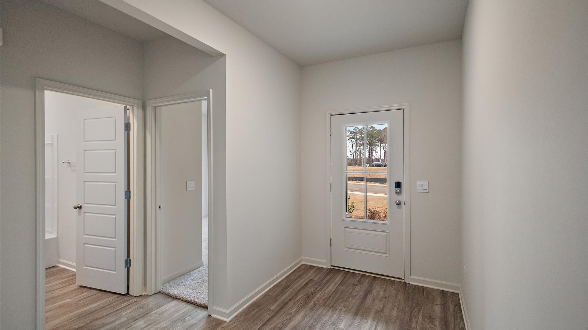 Front entryway and foyer with hardwood floors and recessed lighting.