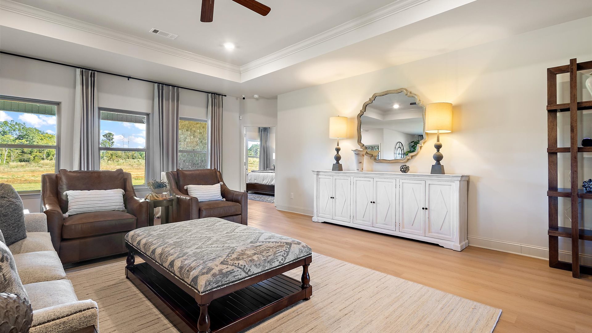 A spacious open floor plan living room, large windows, hardwood floors, and tray ceilings.