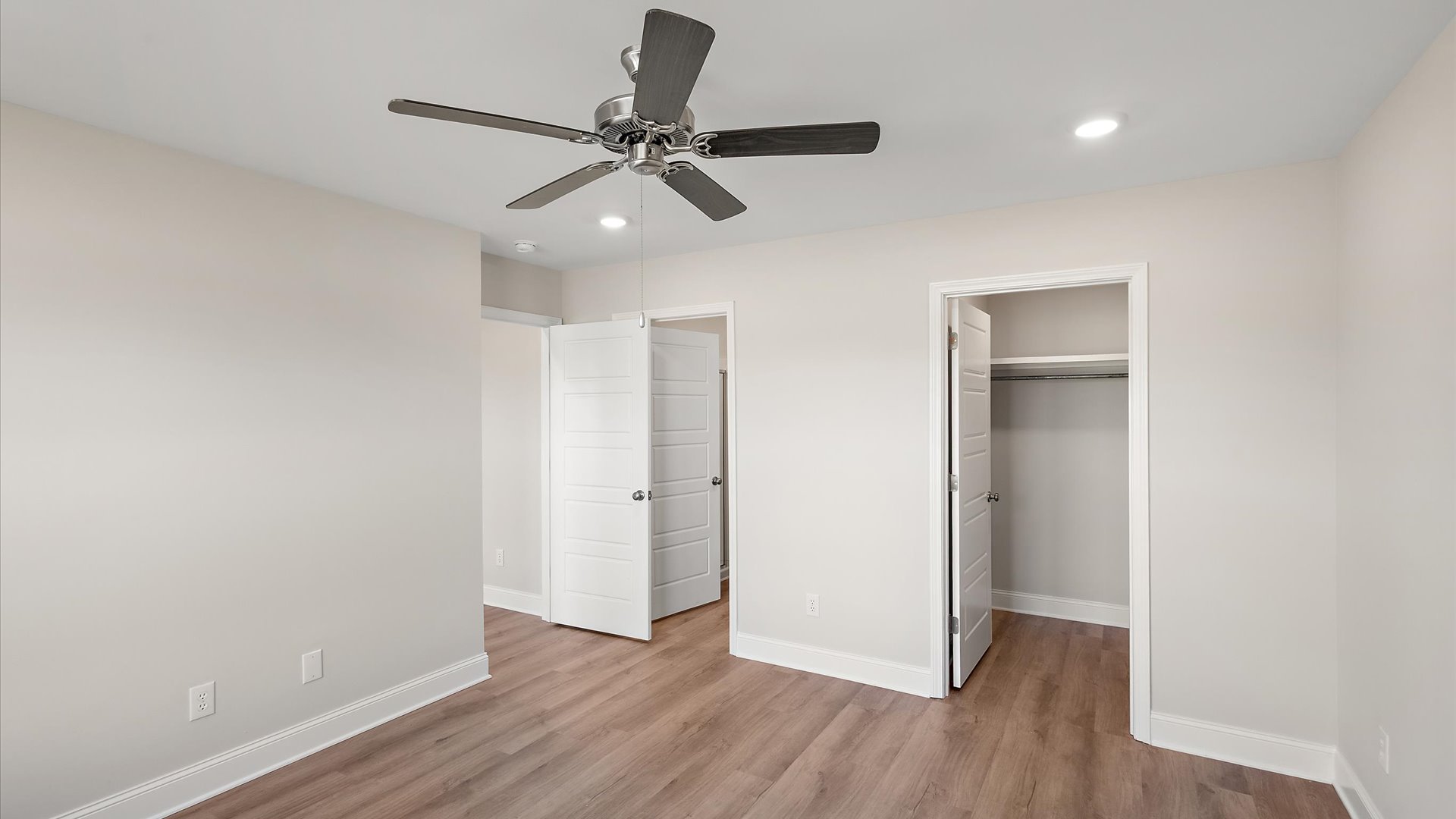 primary bedroom with hardwood floors, recessed lighting, ceiling fan, and walk in closet