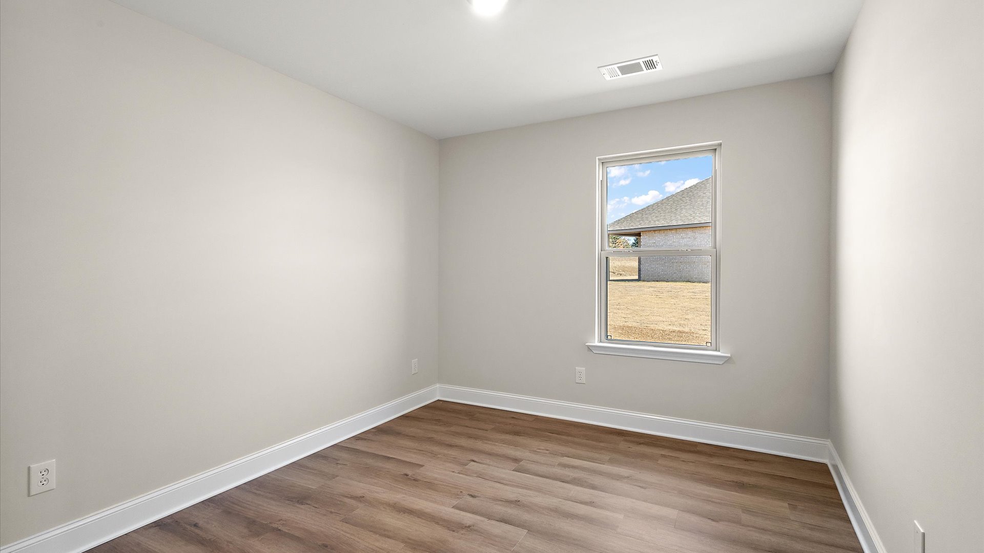 additional bedroom with hardwood floors and window
