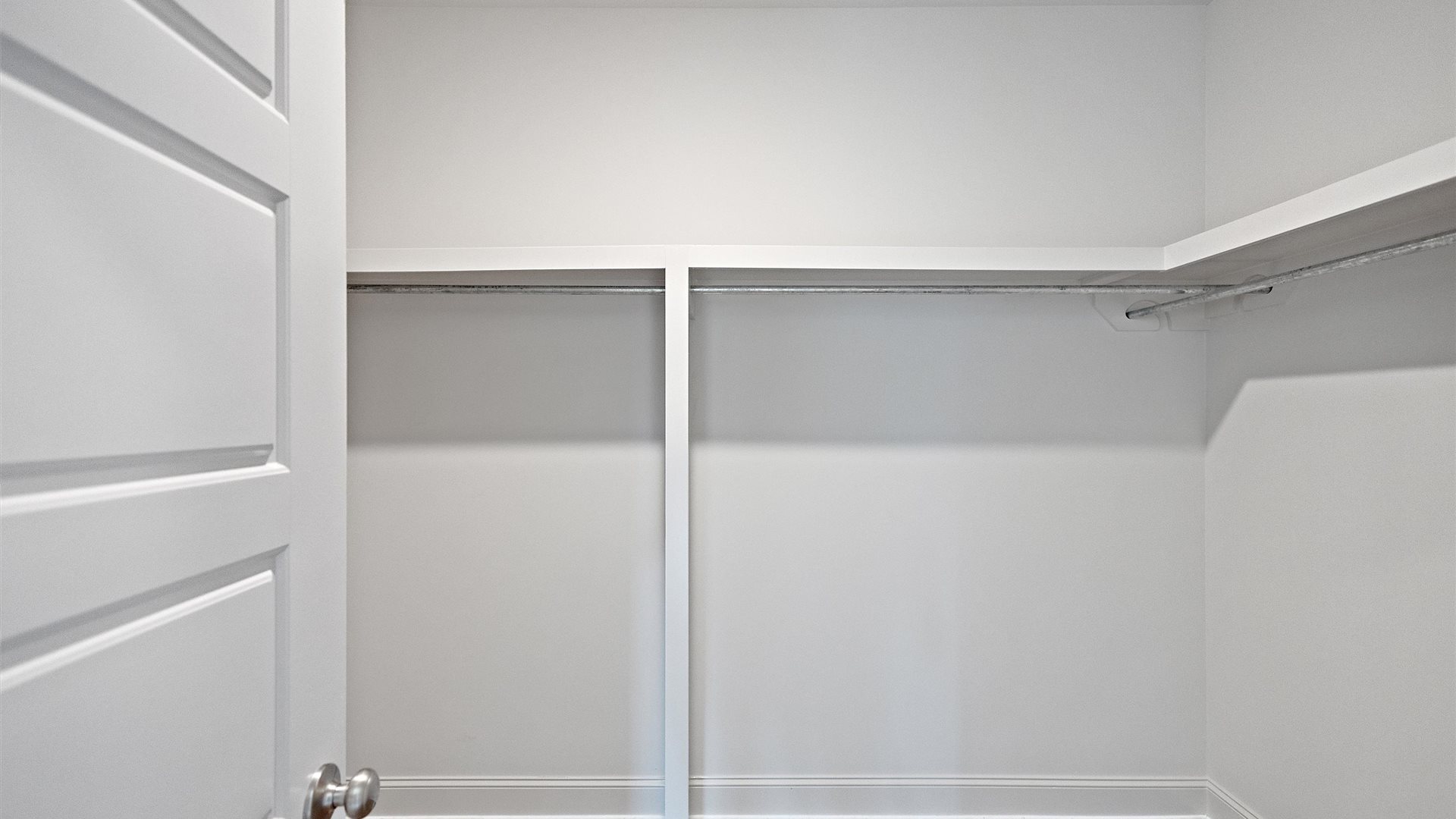 spacious primary closet featuring built in shelves
