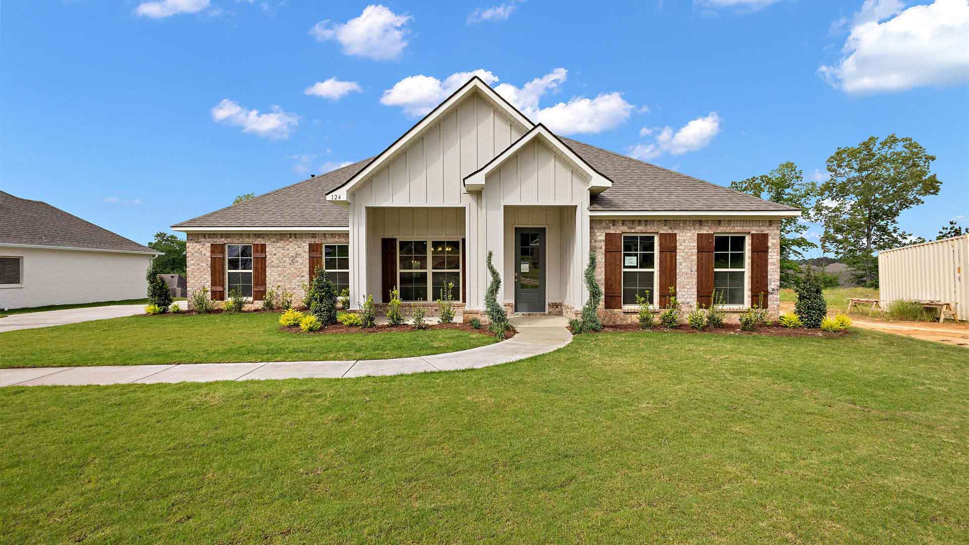 Front exterior of the McKenzie floorplan featuring white siding, light brown brick accents and brown shutters