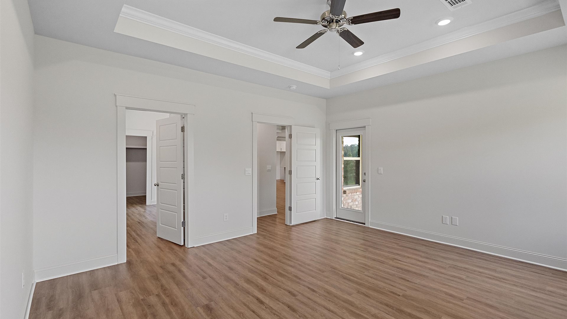 bedroom with brown flooring, white walls and a view of the doors leading to the closet, and hallway