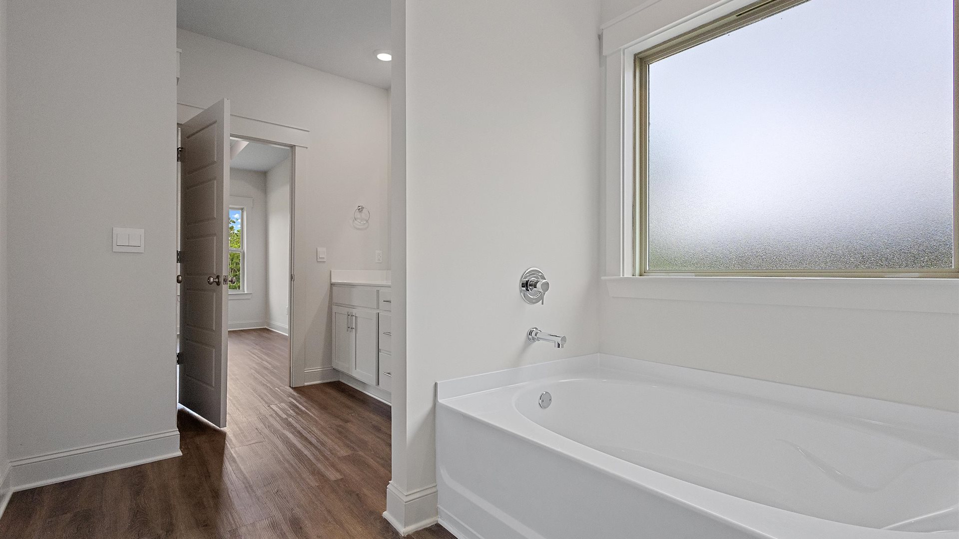 stand alone bath tub in the primary bathroom with a screened window above