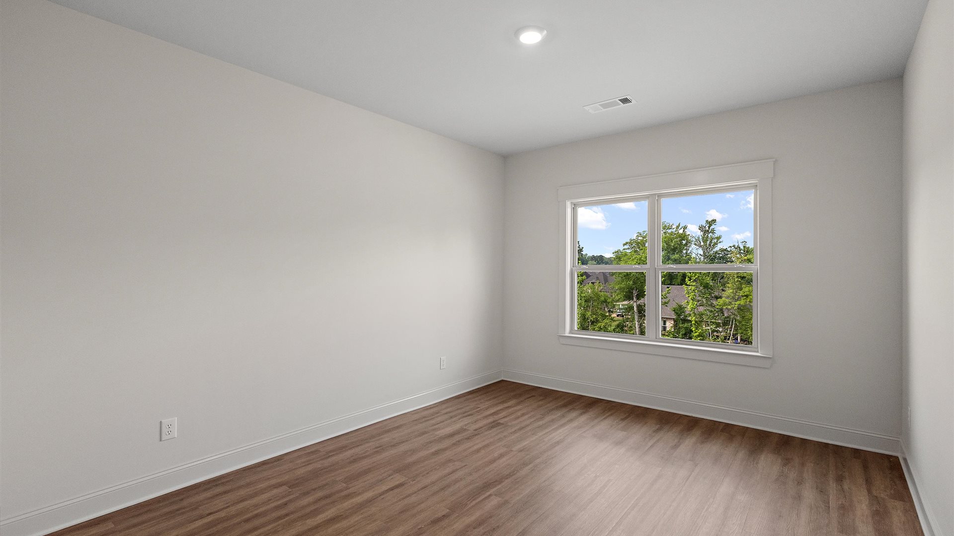 bedroom with brown flooring, and white walls, and a large window on the back wall