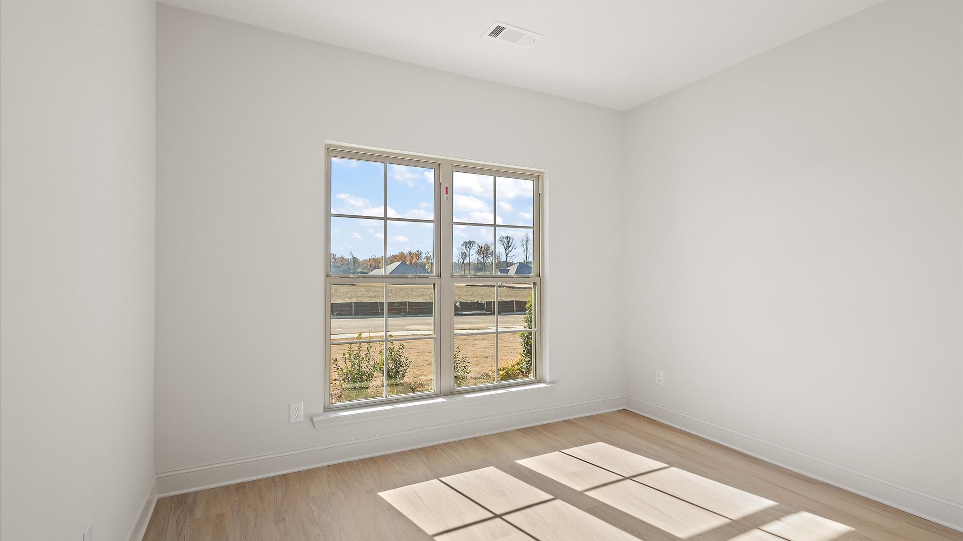 additional bedroom with hardwood floors and window
