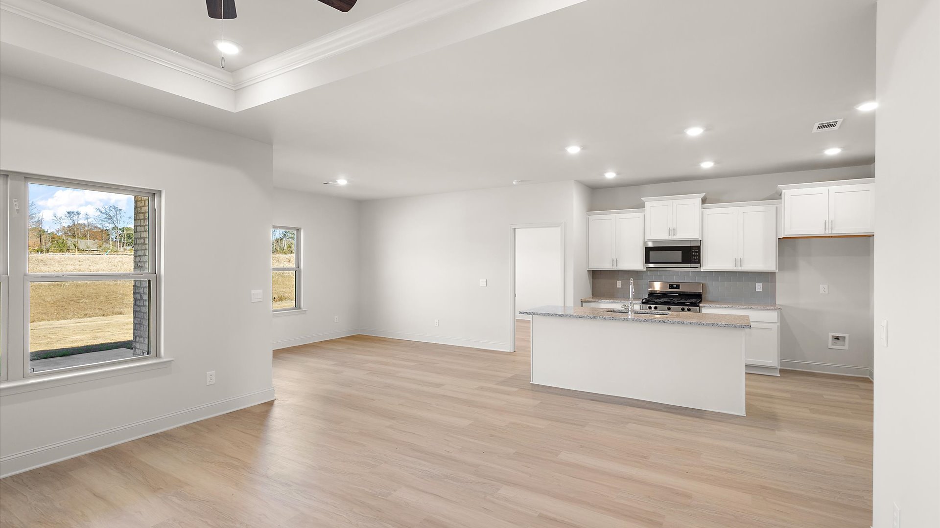 kitchen overlooking the mail living space with quartz countertop, back splash, and stainless steel appliances