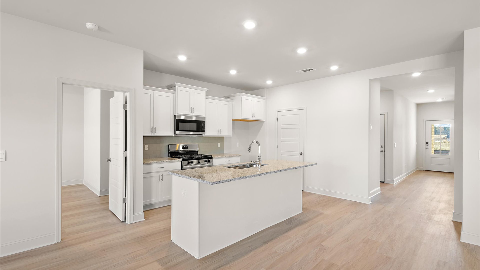 kitchen overlooking the mail living space with quartz countertop, back splash, and stainless steel appliances