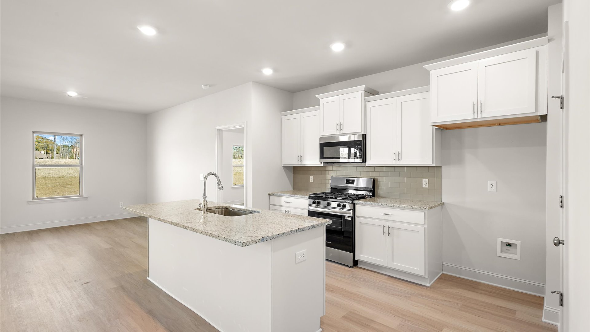 kitchen overlooking the mail living space with quartz countertop, back splash, and stainless steel appliances