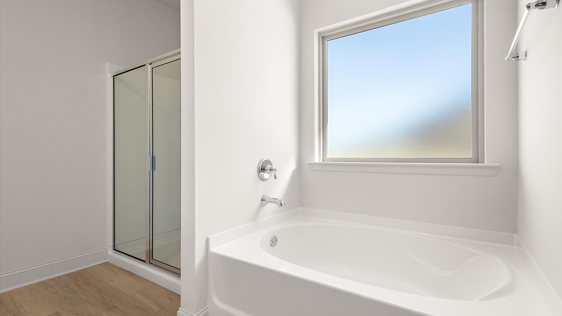garden tub with frosted window for light, adjacent walk in shower
