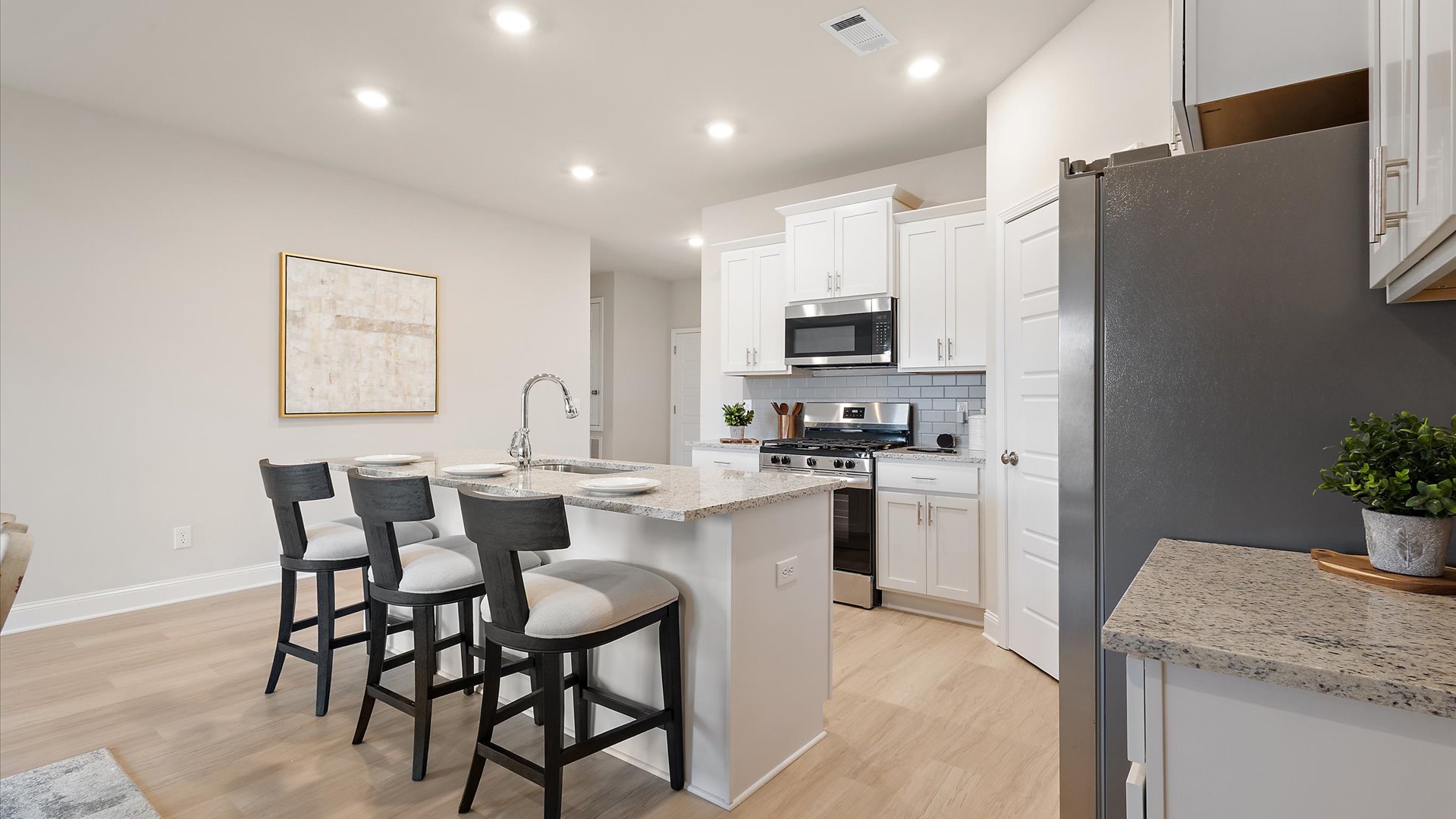 open kitchen with bar top overlooking the dining area with hardwood flooring and stainless steel appliances