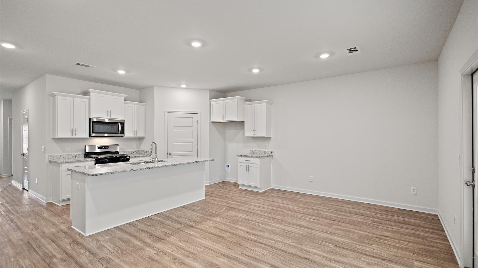 Spacious kitchen with granite countertops, island, and stainless-steel appliances.