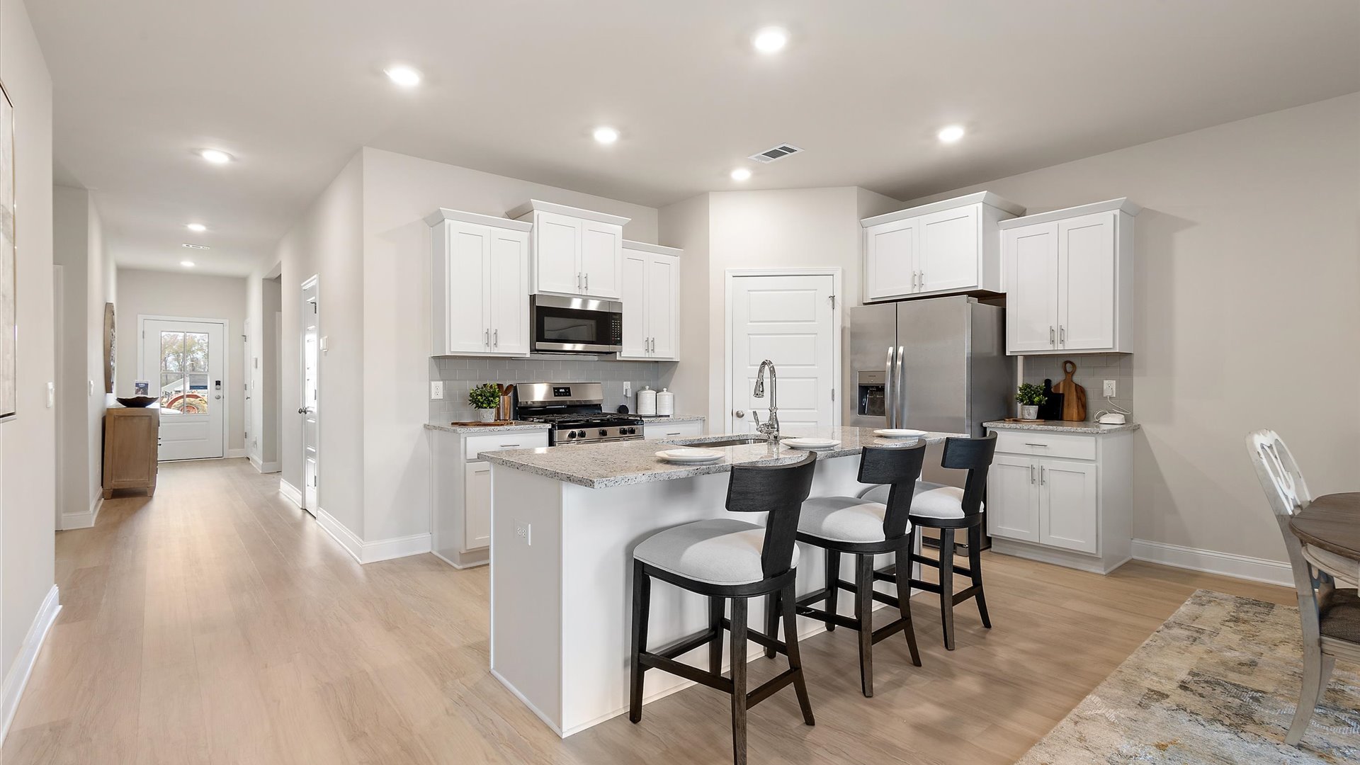 open kitchen with bar top overlooking the dining area with hardwood flooring and stainless steel appliances