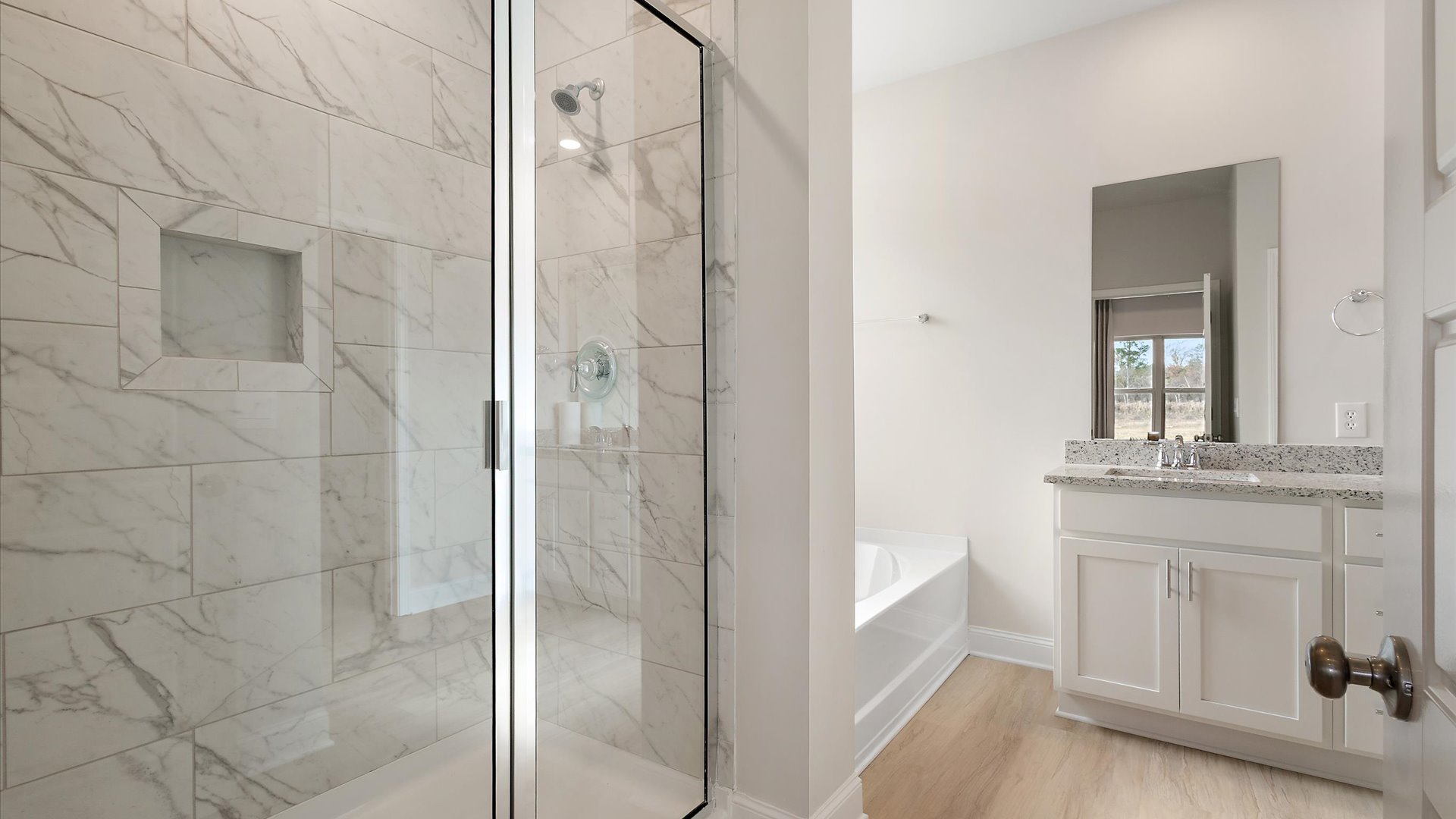 walk in shower adjacent to garden tub, hardwood flooring leading to double vanity