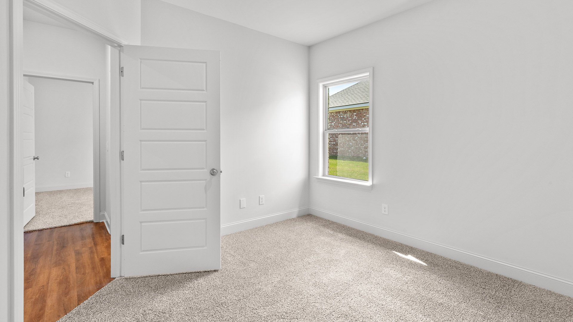 Carpeted bedroom three with a single window and a view of the hall and bedroom two.