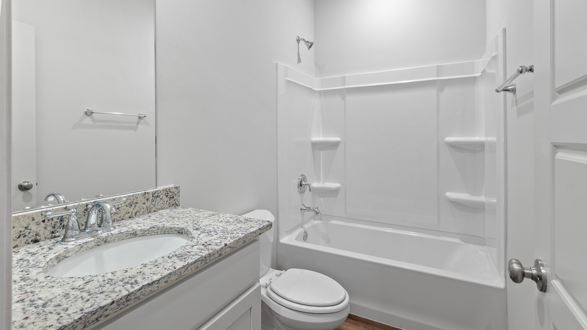 Second full bathroom with a single vanity sink, white shaker style cabinets, and a white shower with a tub.