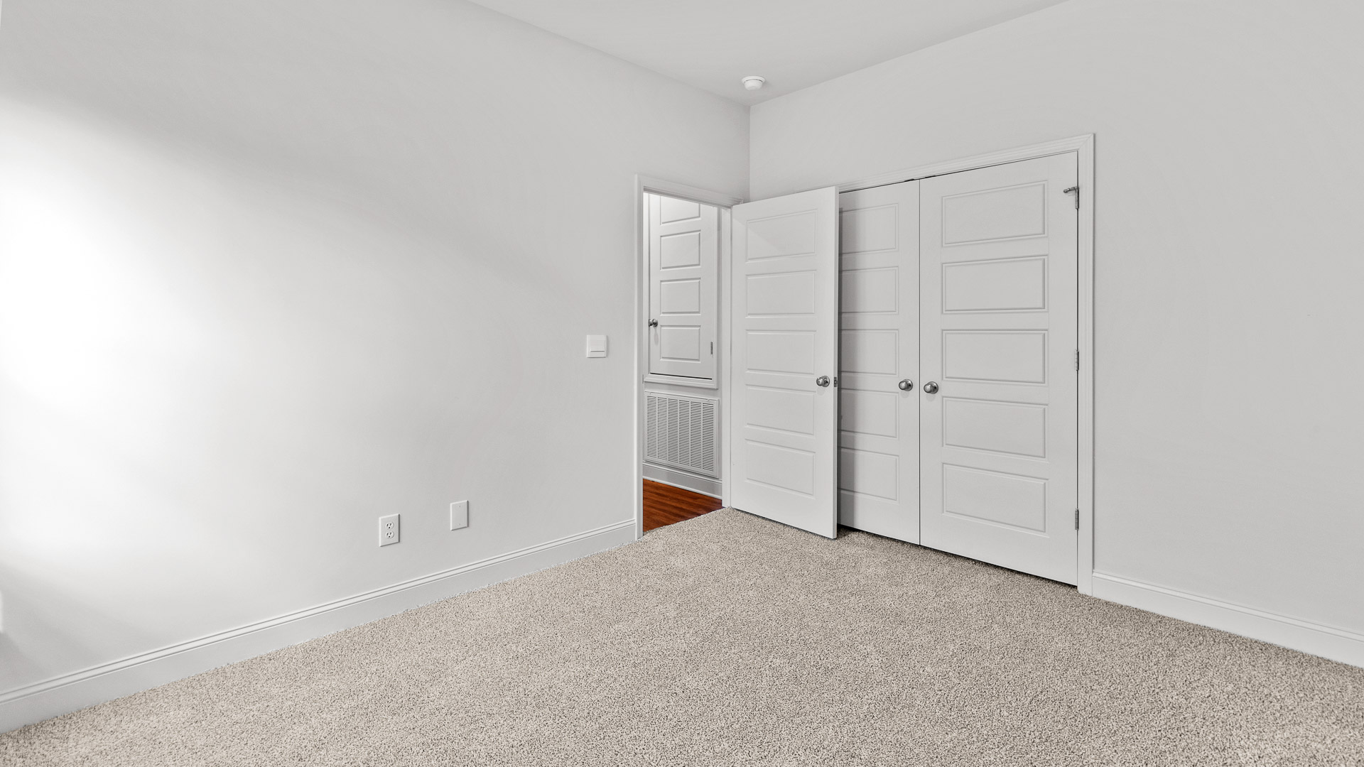 Carpeted primary bedroom two with a closet and a view of the hall.
