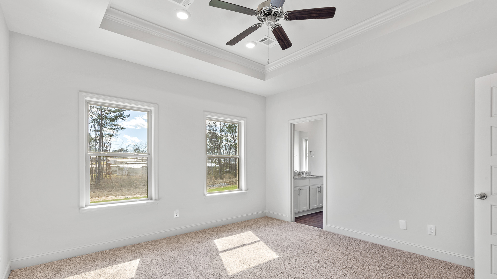 Carpeted primary bedroom one with two single windows and ensuite bathroom.