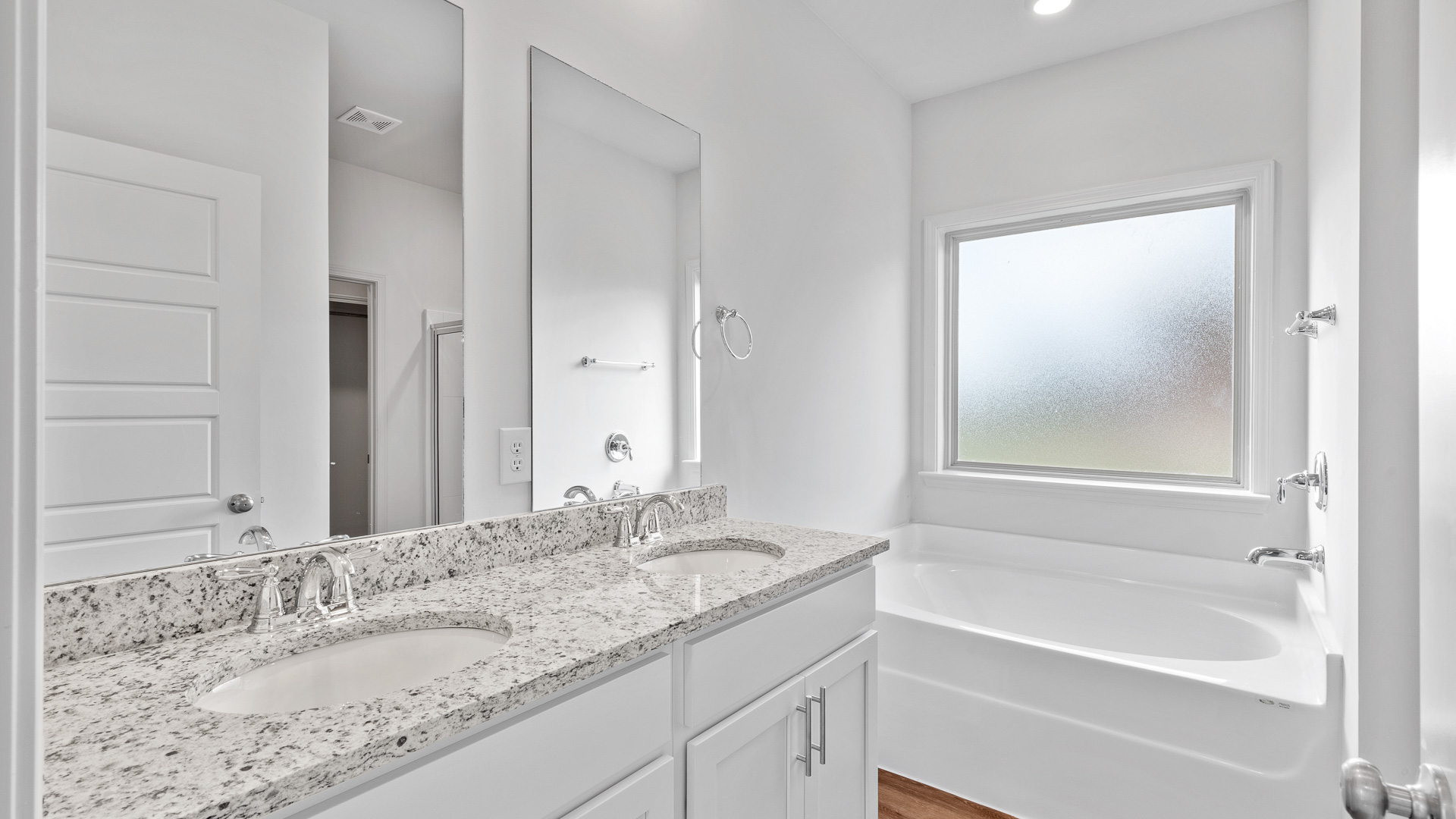 Primary bathroom has double vanity sinks, granite countertops, white shaker style cabinets, garden tub and a walk-in shower.