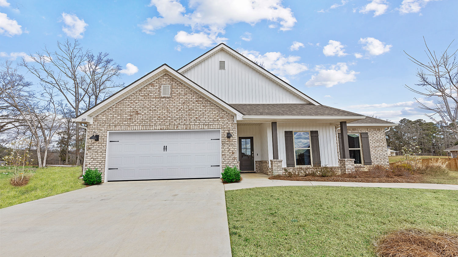 front exterior of a one story home with light brick accents, white siding and black shutters
