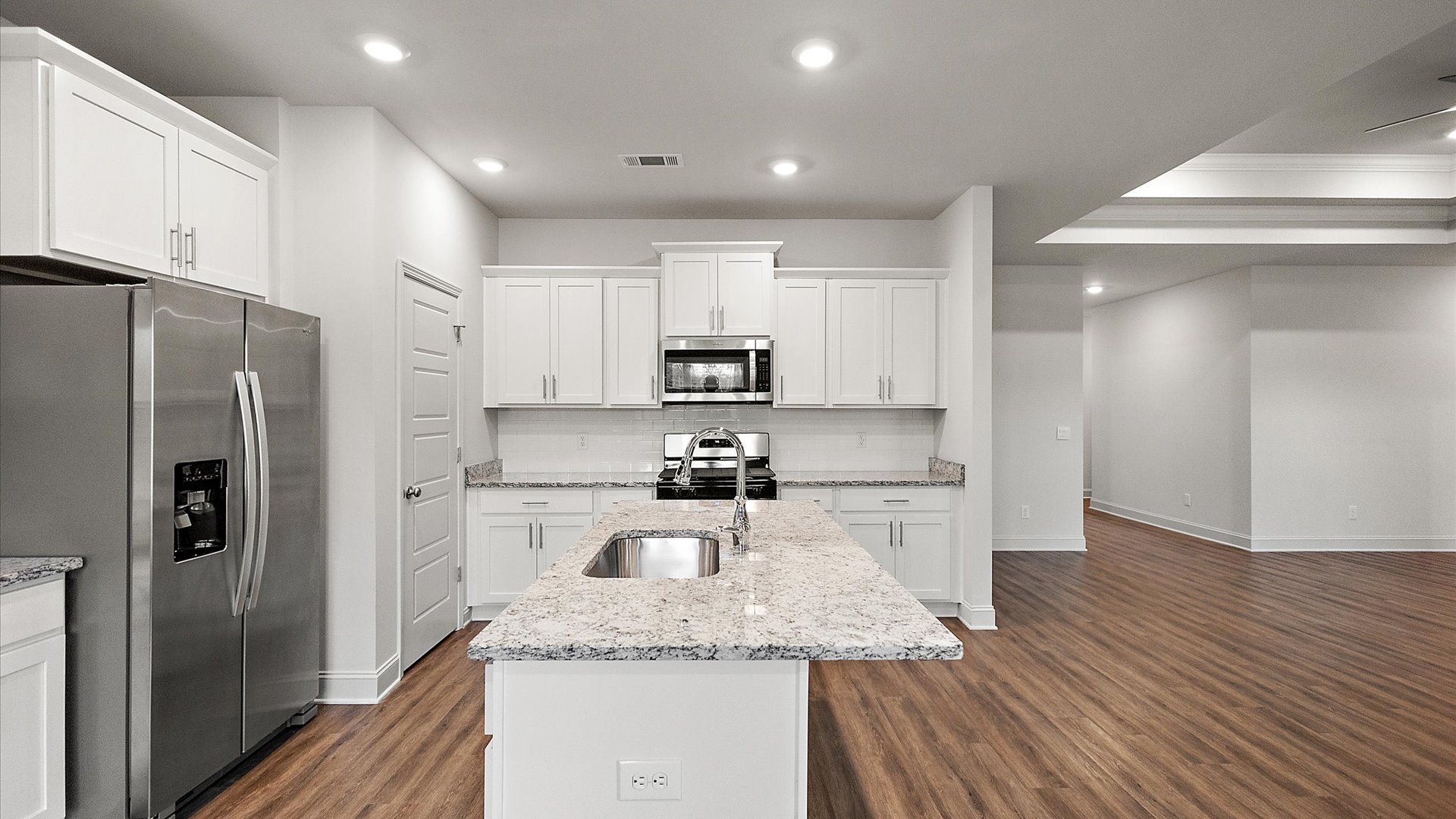 The single-story home plan has a spacious kitchen and island with granite countertops and appliances.