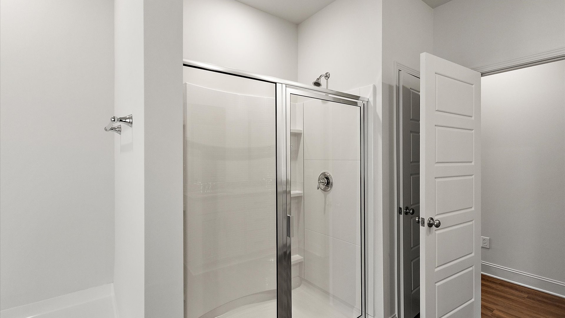 Walk-in shower with glass door and built-in shelving.