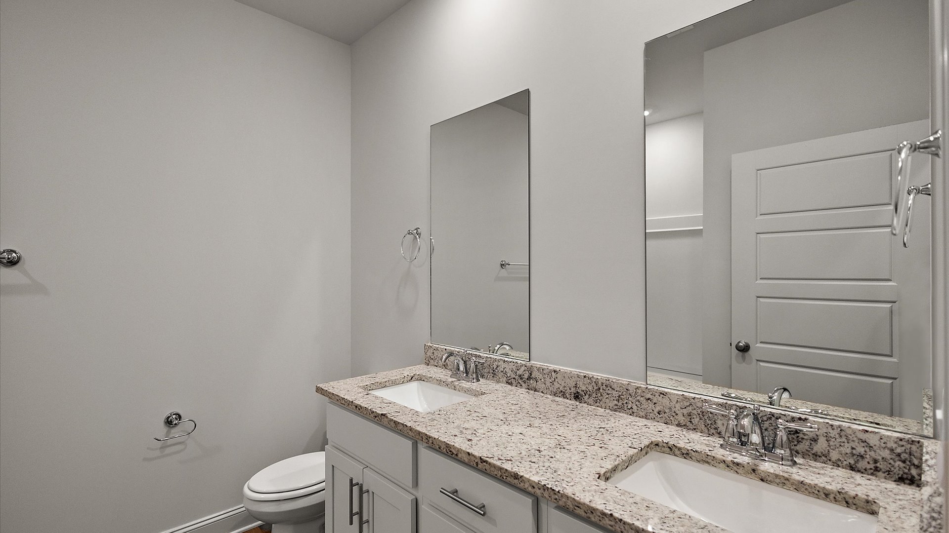 Double vanity with granite countertops, and bright light fixtures.
