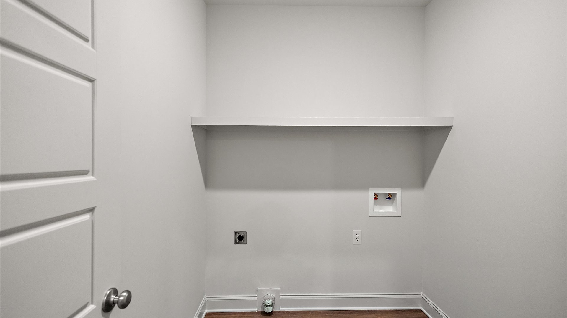 Spacious laundry room with wooden shelving for storage.