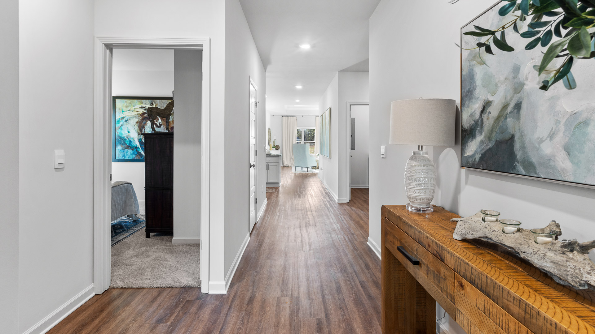 Entry hallway of the Rhett floorplan featuring rich brown flooring, white walls and an entry table to the right