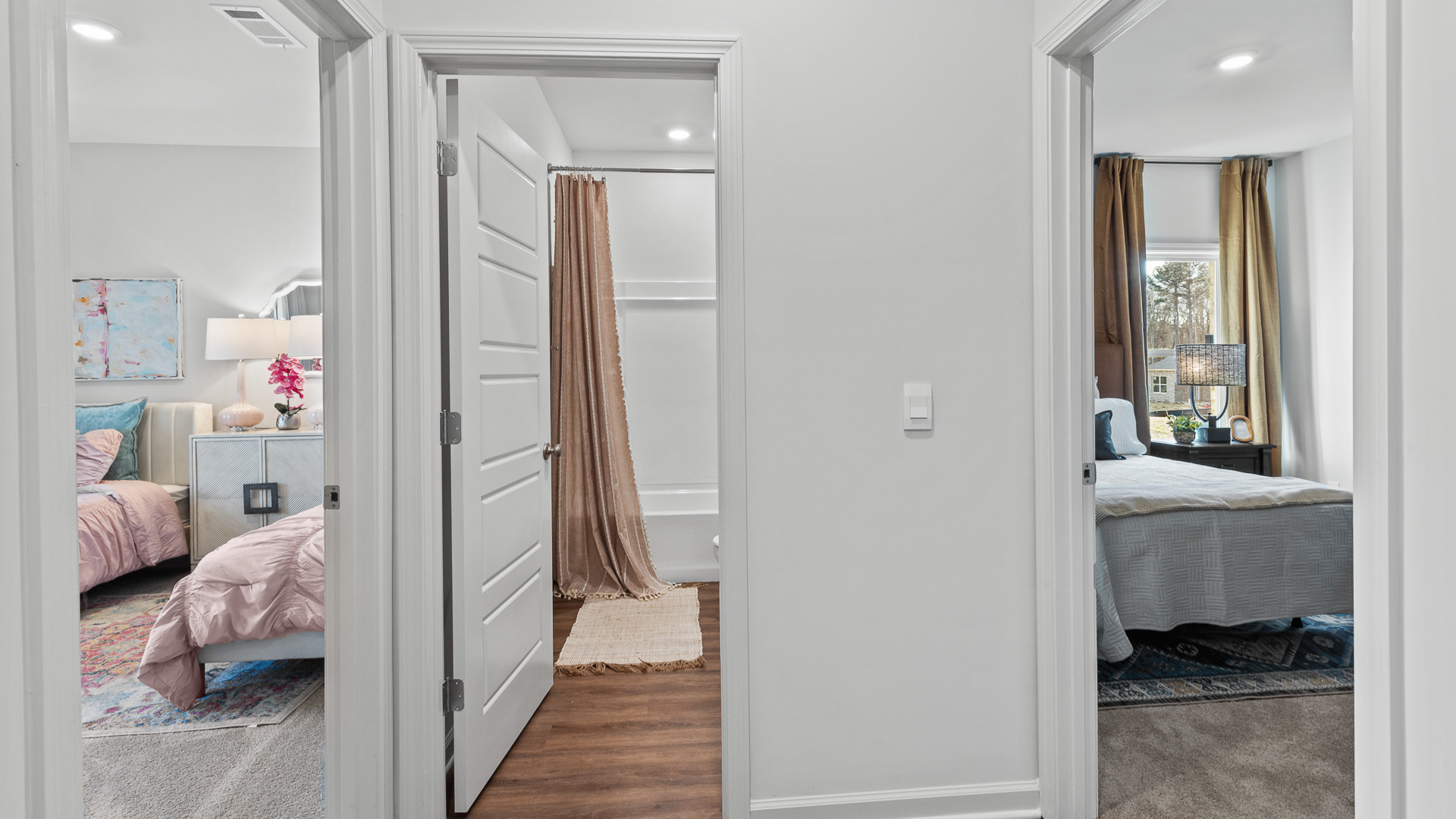 Hallway view of two bedrooms and a bathroom in the middle