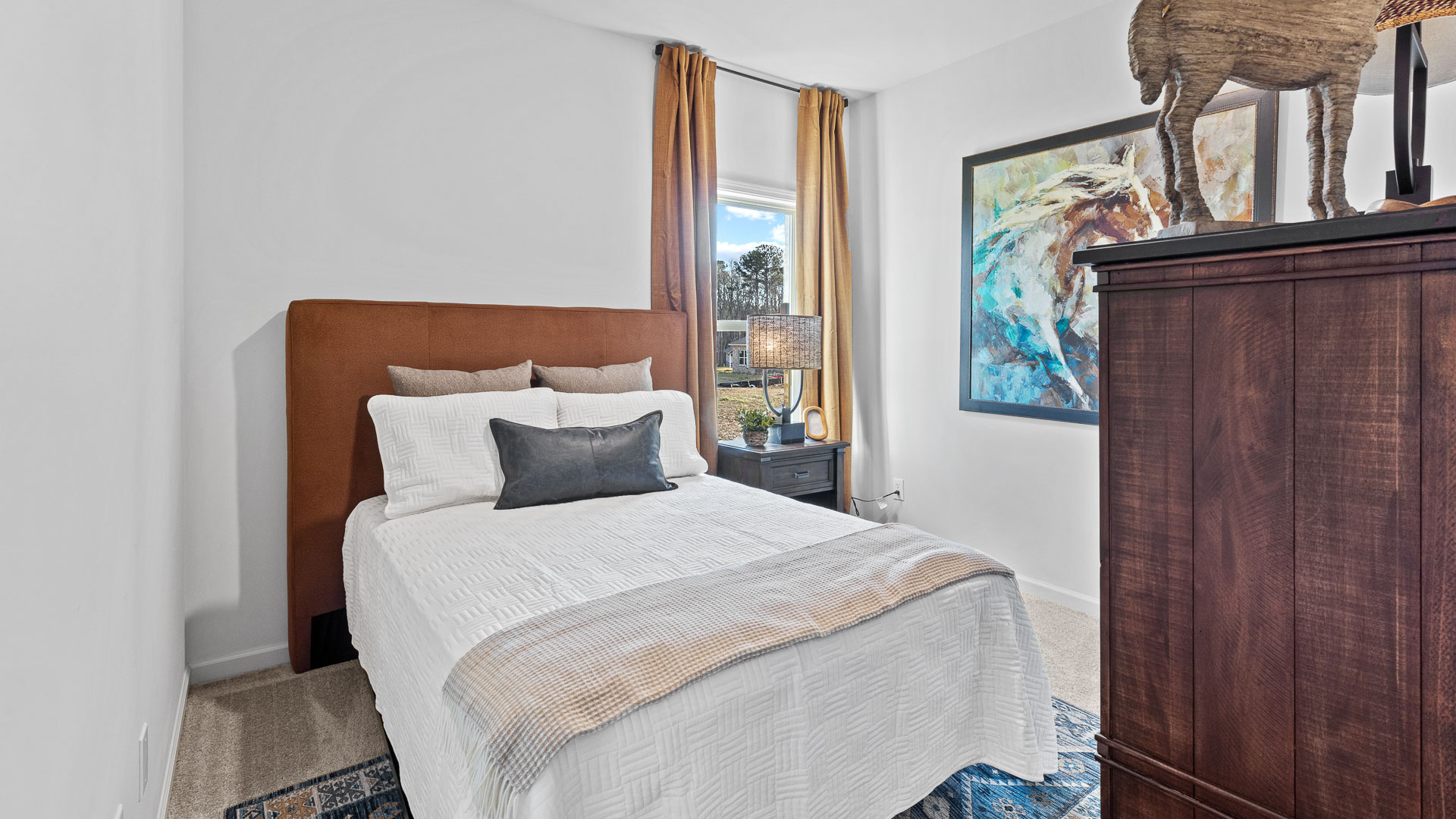 bedroom featuring a bed with brown and grey decorative tons and a window to the right of the bed