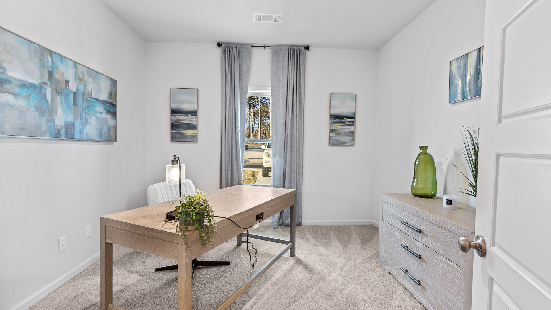 bedroom turned into a home office with a desk and green and blue decor