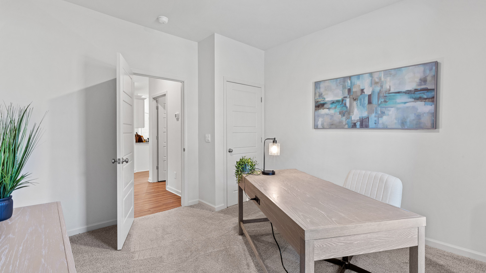 bedroom turned into a home office with a desk and green and blue decor