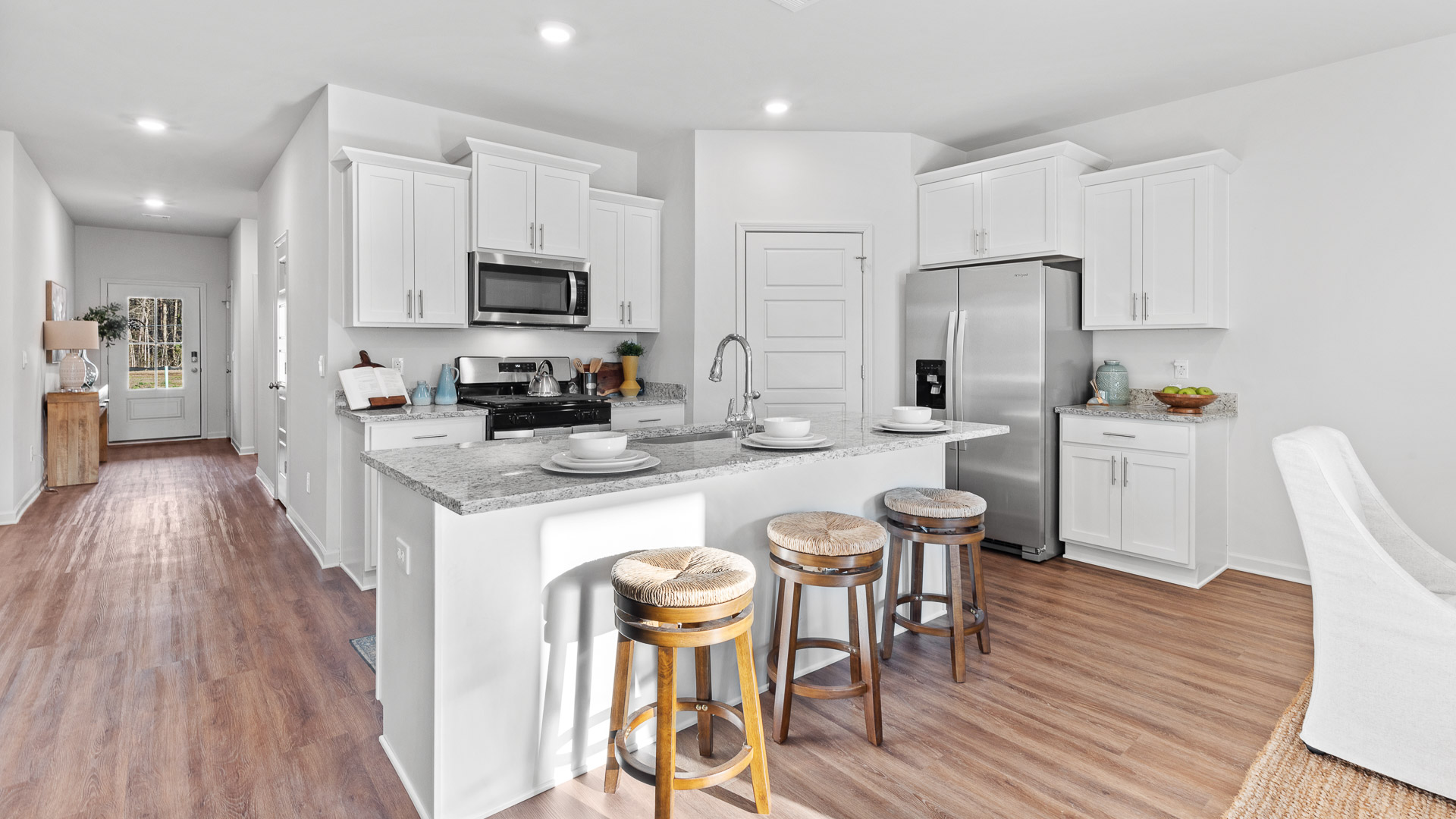 spacious kitchen featuring white cabinetry, large island, and stainless steel appliances