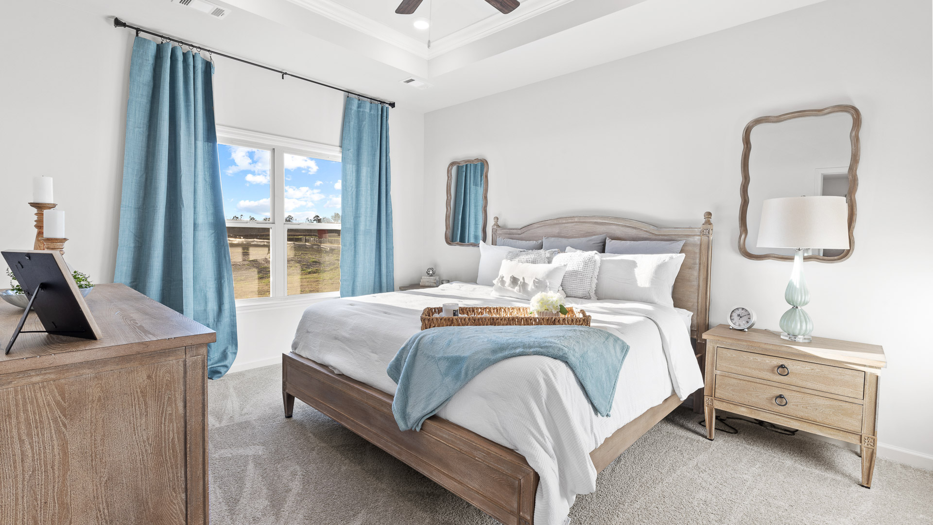 primary bedroom featuring a king bed with night stands on either side with mirrors above, decorated in blue tones