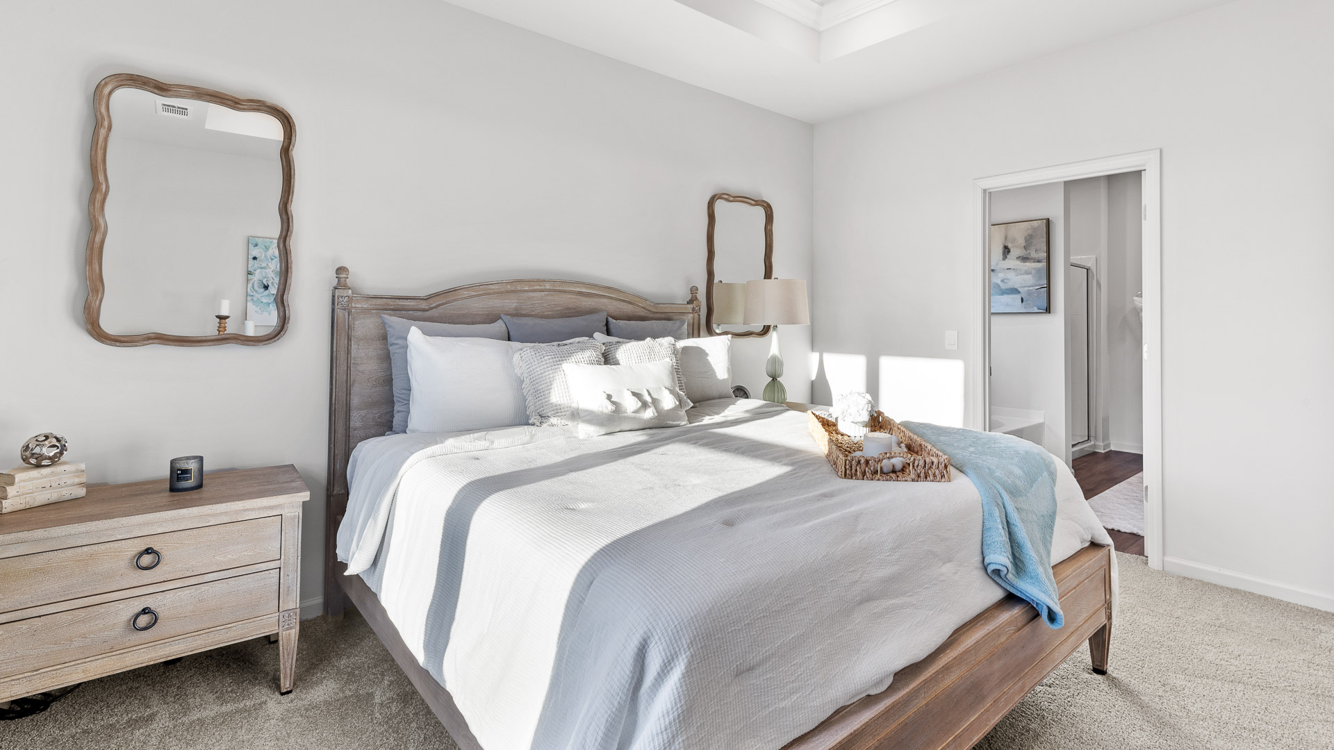 primary bedroom featuring a king bed with night stands on either side with mirrors above, decorated in blue tones