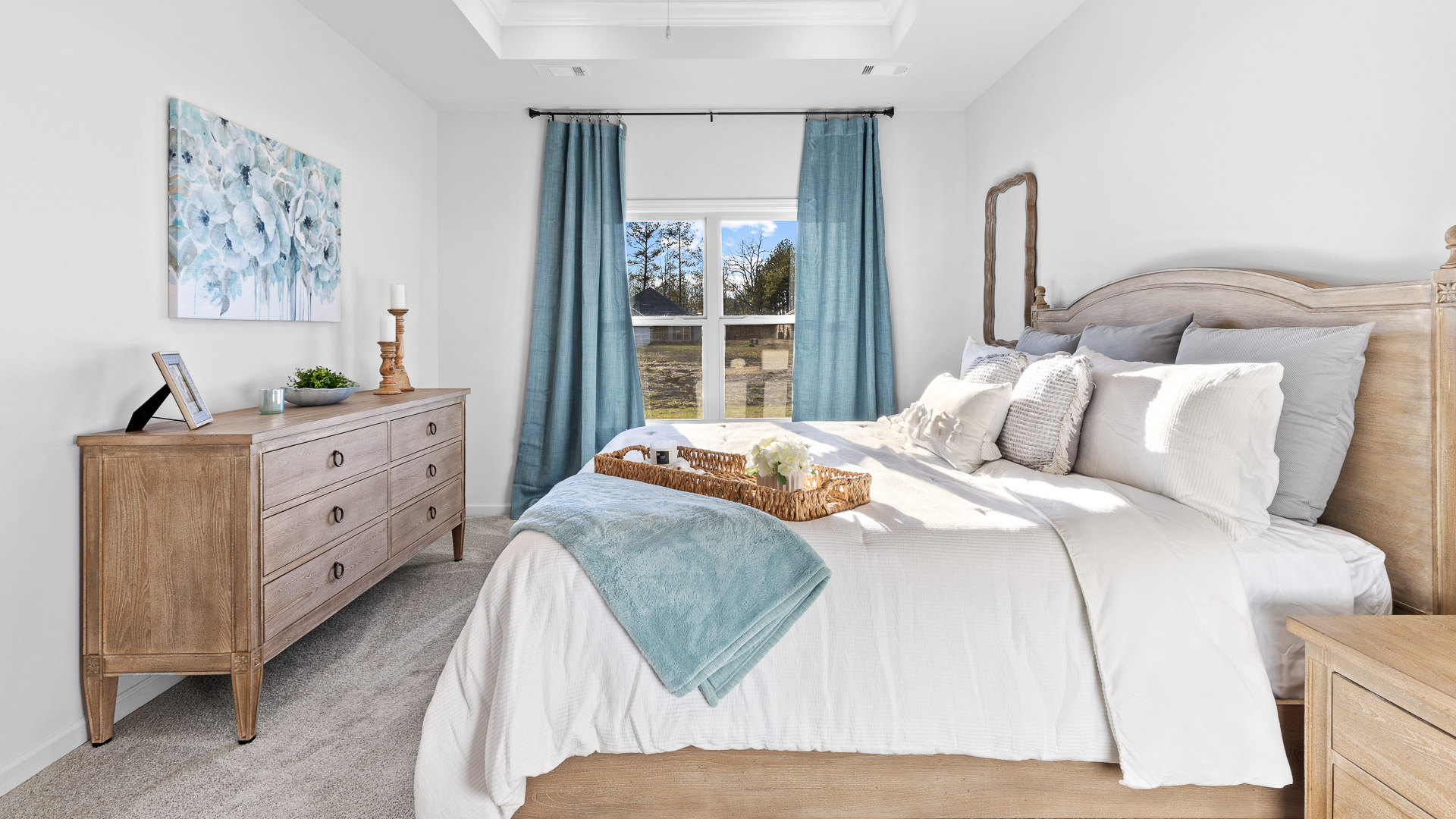primary bedroom featuring a king bed with night stands on either side with mirrors above, decorated in blue tones