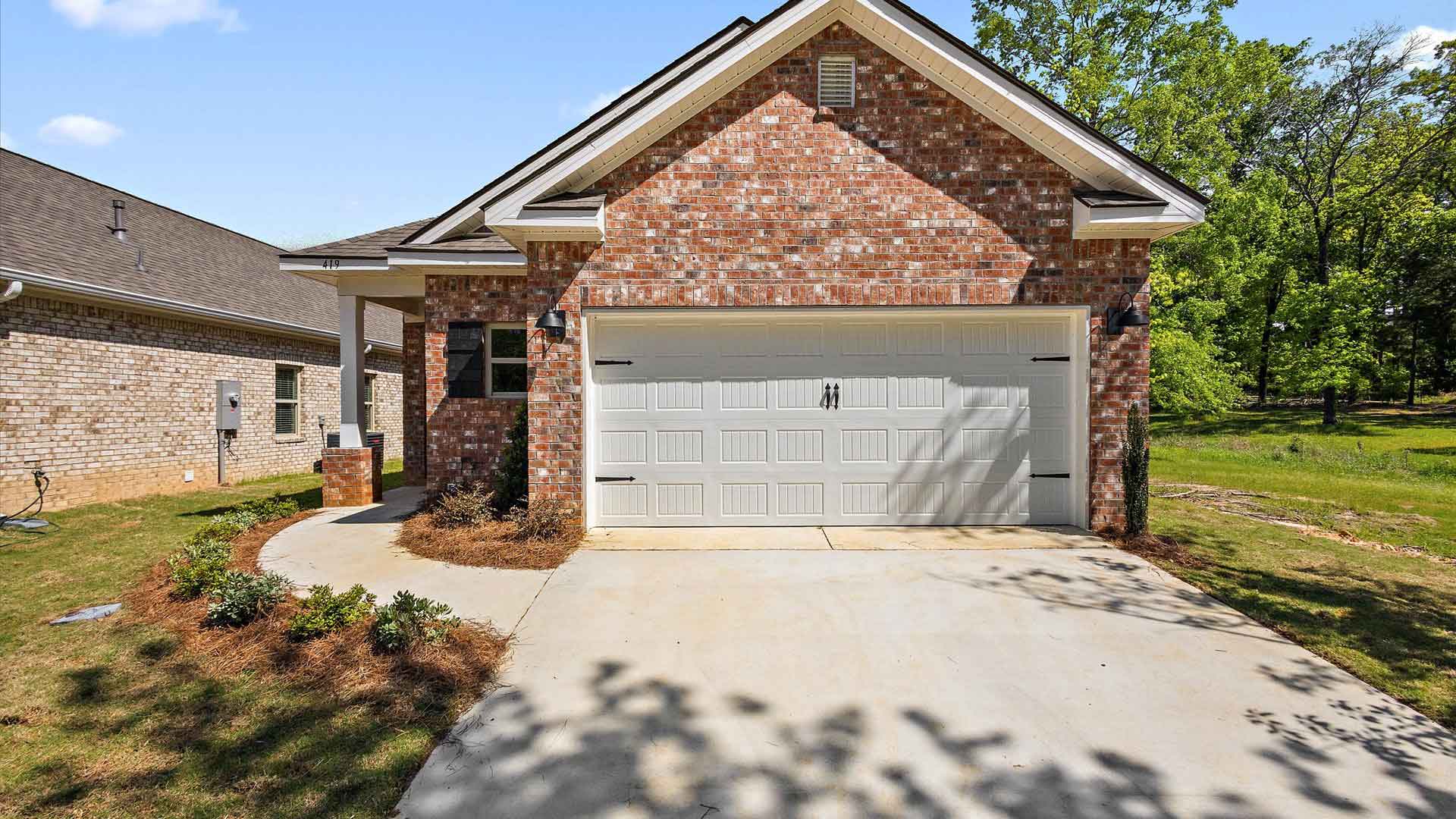 one-story exterior home front view with brown brick, a window, and a two-car garage.