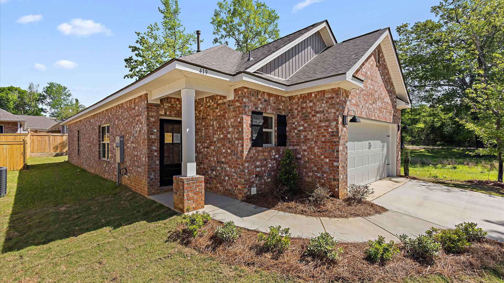 one-story exterior home left side view with brown brick, a window, and a two-car garage.